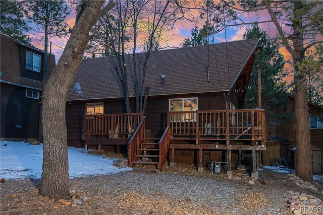a view of a house with a wooden deck and a wooden fence