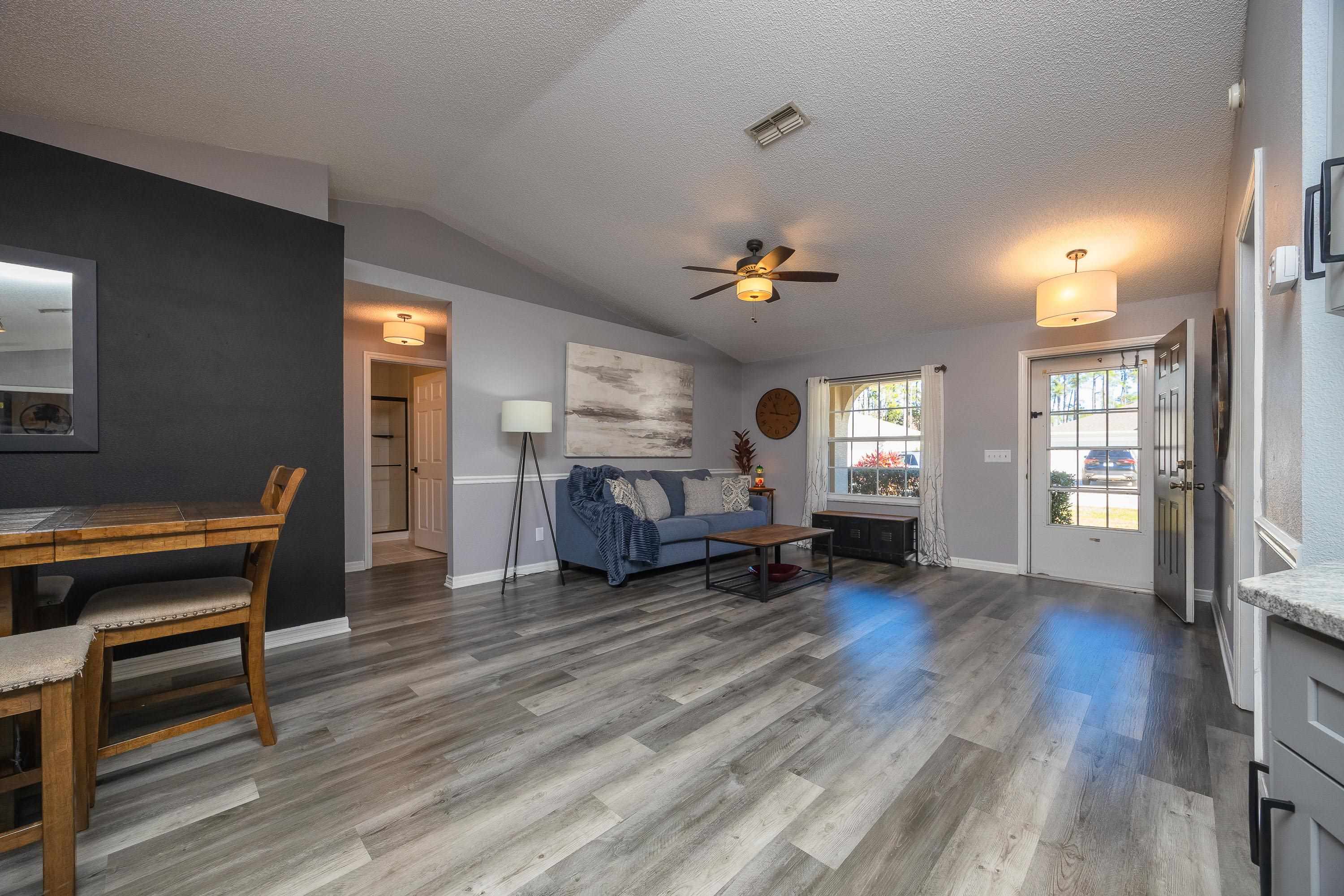 5 Rippling Place Palm Coast, FL 32164 - Photo 11 of 50 Living area featuring vaulted ceiling, a ceiling fan, a textured ceiling, and light wood-style floors