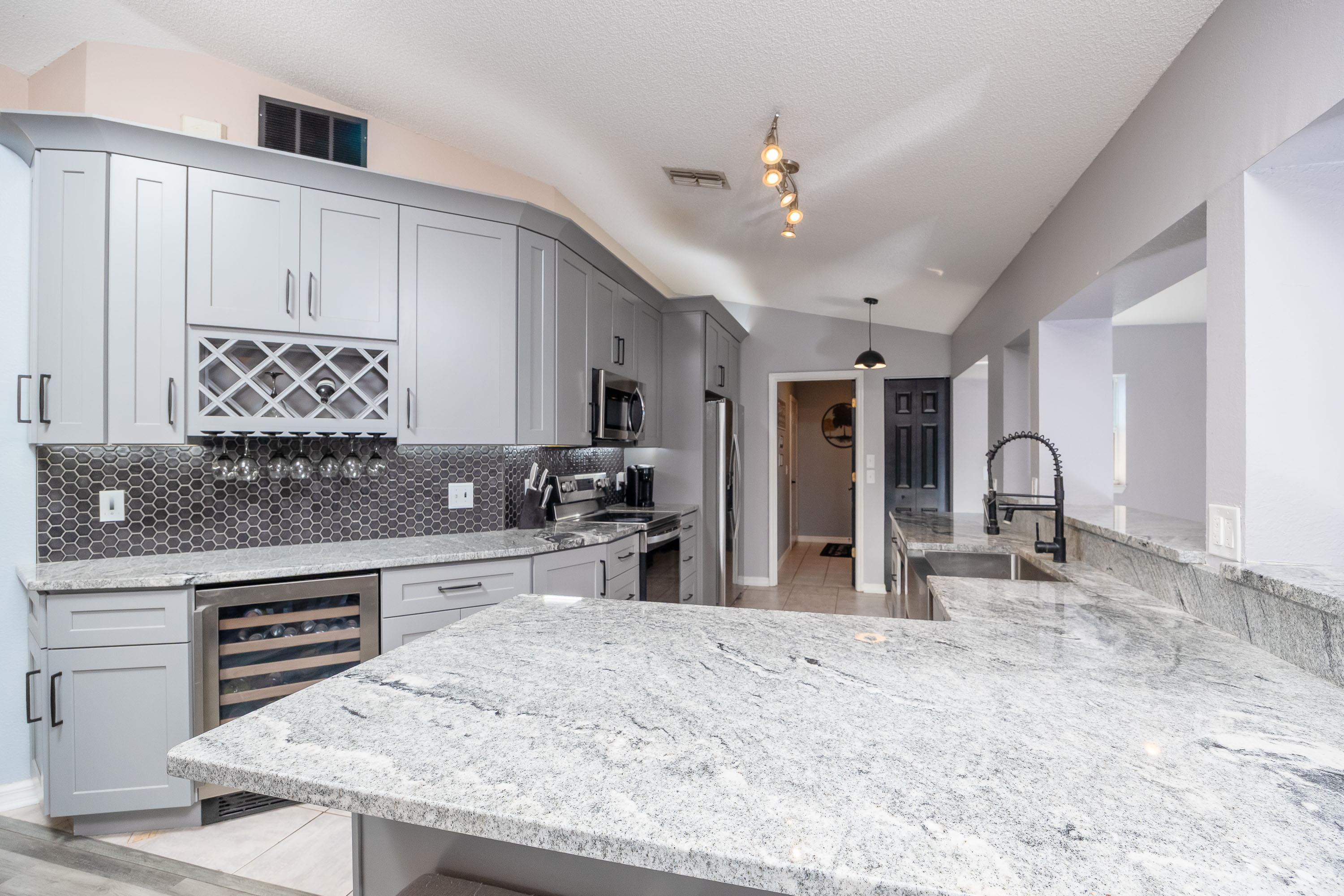 5 Rippling Place Palm Coast, FL 32164 - Photo 14 of 50 Kitchen with light stone counters, vaulted ceiling, wine cooler, gray cabinetry, and stainless steel appliances