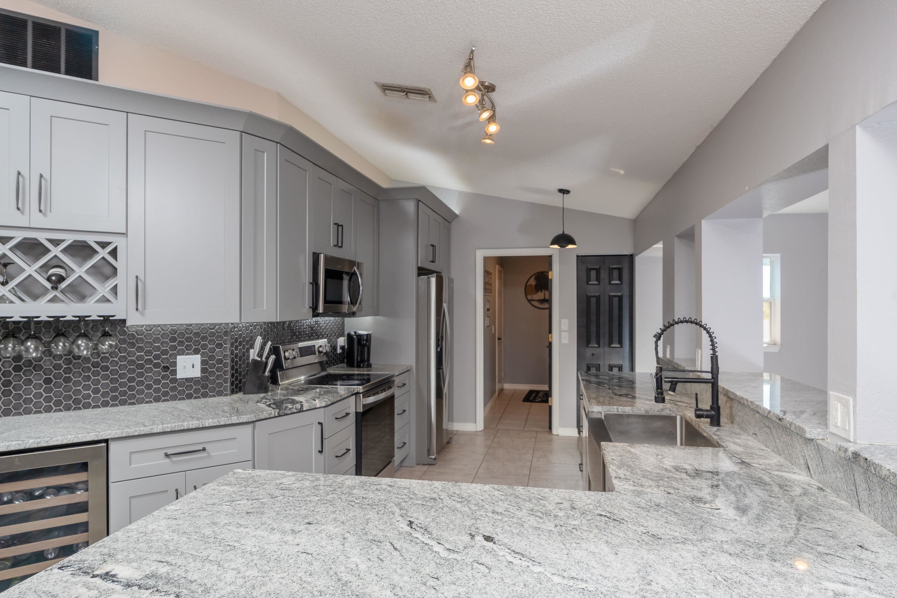 5 Rippling Place Palm Coast, FL 32164 - Photo 15 of 50 Kitchen with stainless steel appliances, light stone countertops, wine cooler, gray cabinets, and backsplash