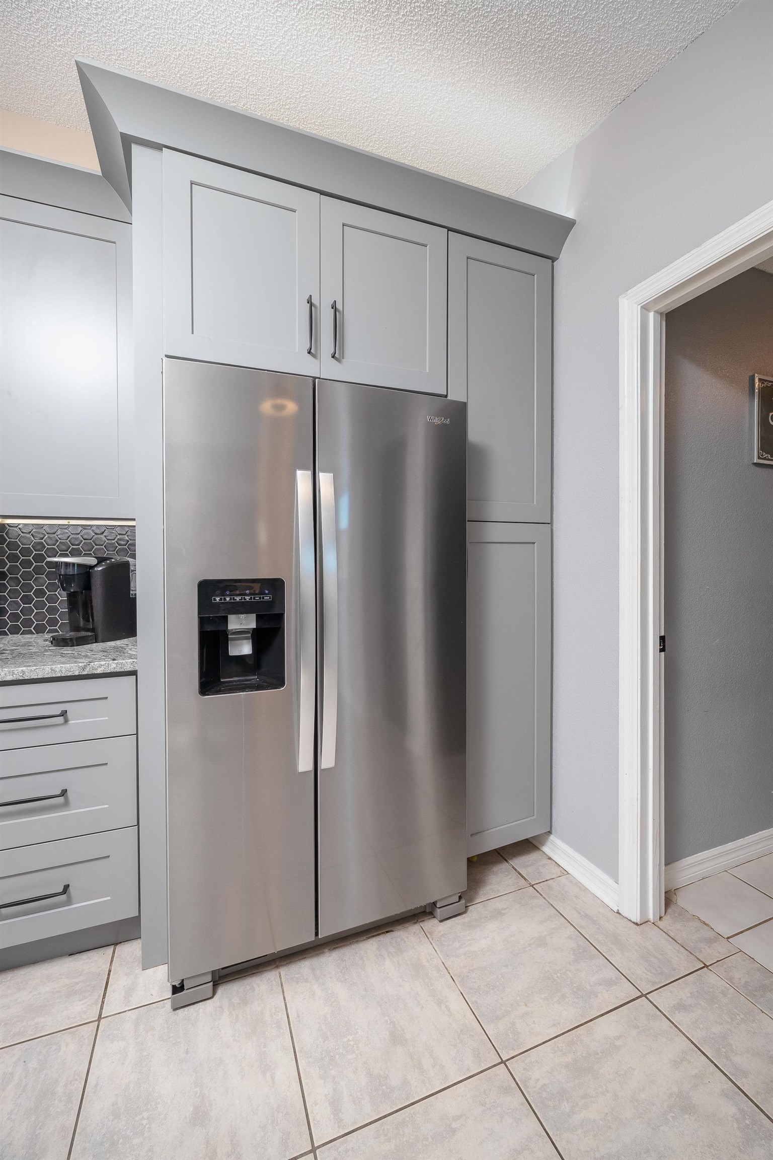 5 Rippling Place Palm Coast, FL 32164 - Photo 16 of 50 Kitchen featuring gray cabinets, stainless steel fridge with ice dispenser, a textured ceiling, light tile patterned floors, and light stone countertops