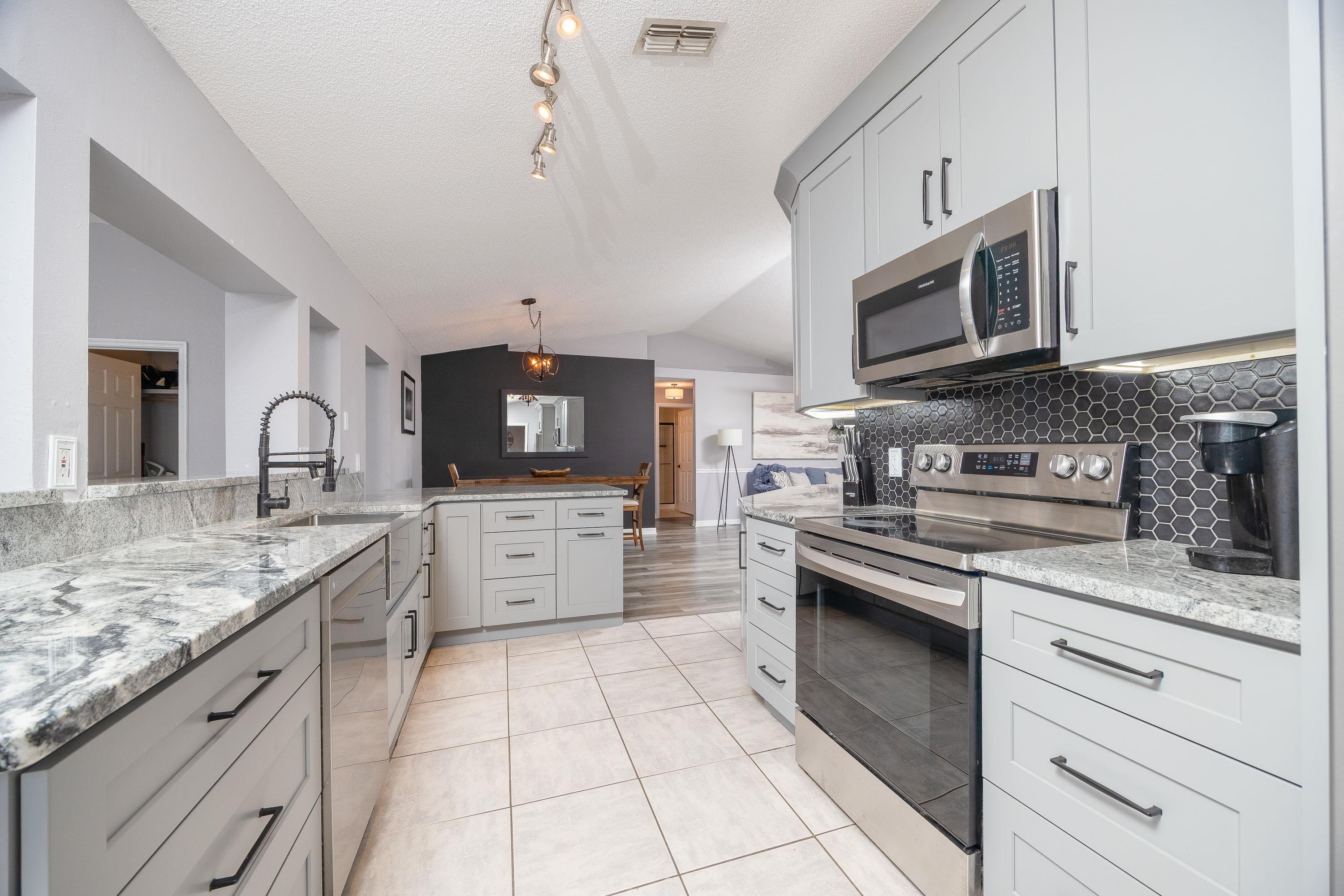 5 Rippling Place Palm Coast, FL 32164 - Photo 17 of 50 Kitchen with stainless steel appliances, lofted ceiling, light stone countertops, hanging light fixtures, and light tile patterned floors