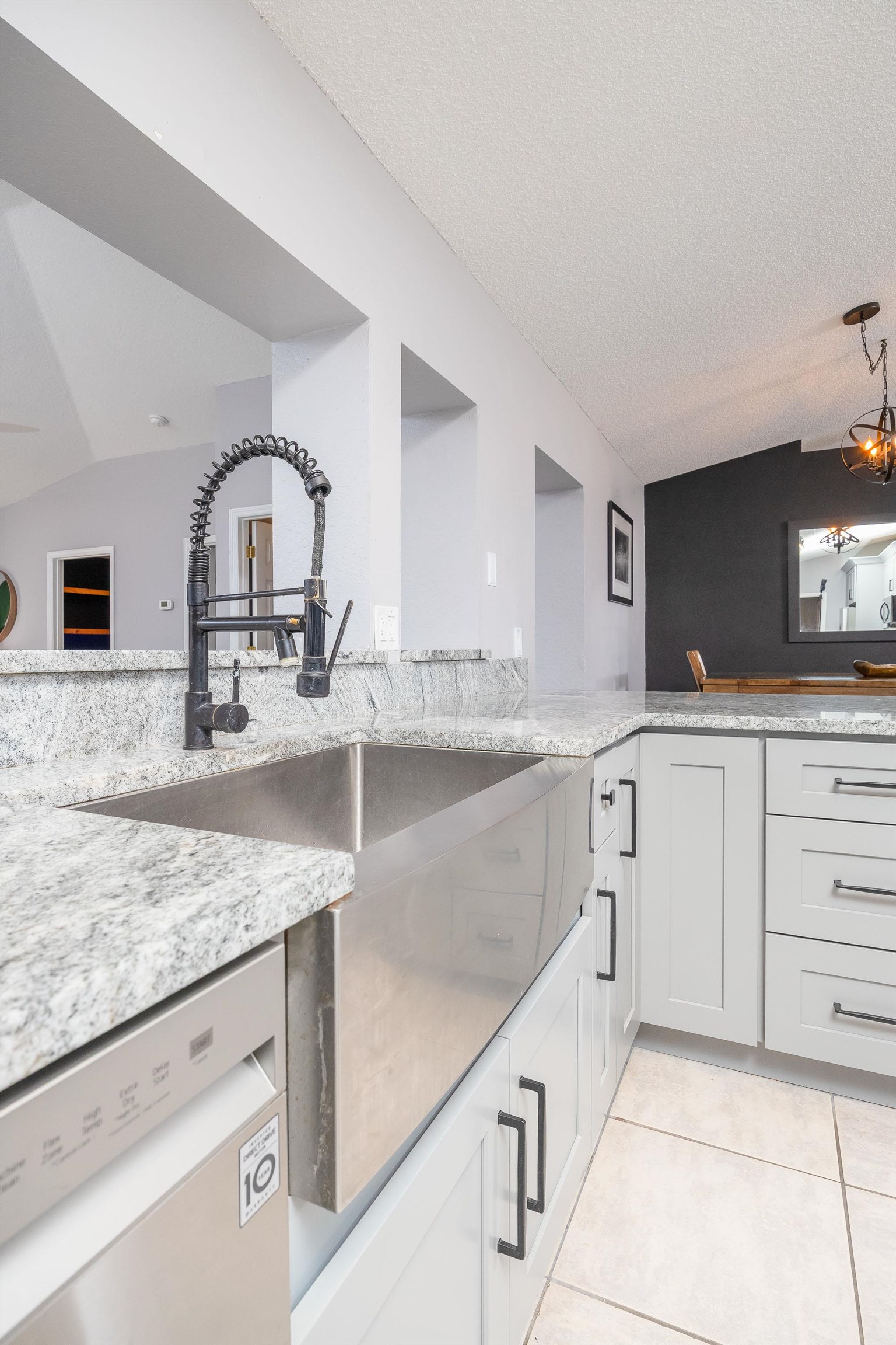 5 Rippling Place Palm Coast, FL 32164 - Photo 18 of 50 Kitchen featuring light stone counters, dishwasher, lofted ceiling, light tile patterned floors, and a textured ceiling