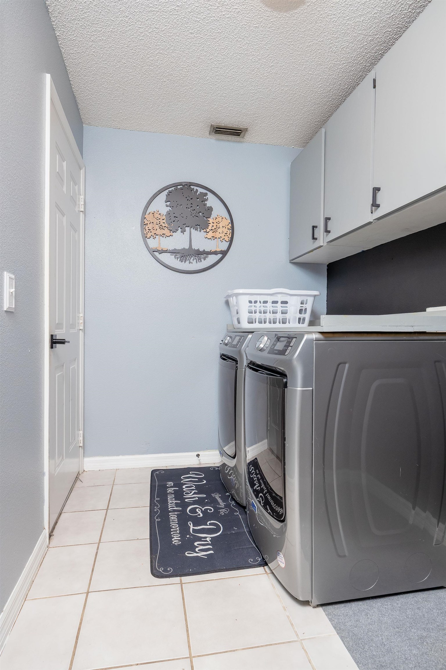 5 Rippling Place Palm Coast, FL 32164 - Photo 19 of 50 Washroom with a textured ceiling, cabinet space, light tile patterned floors, and separate washer and dryer