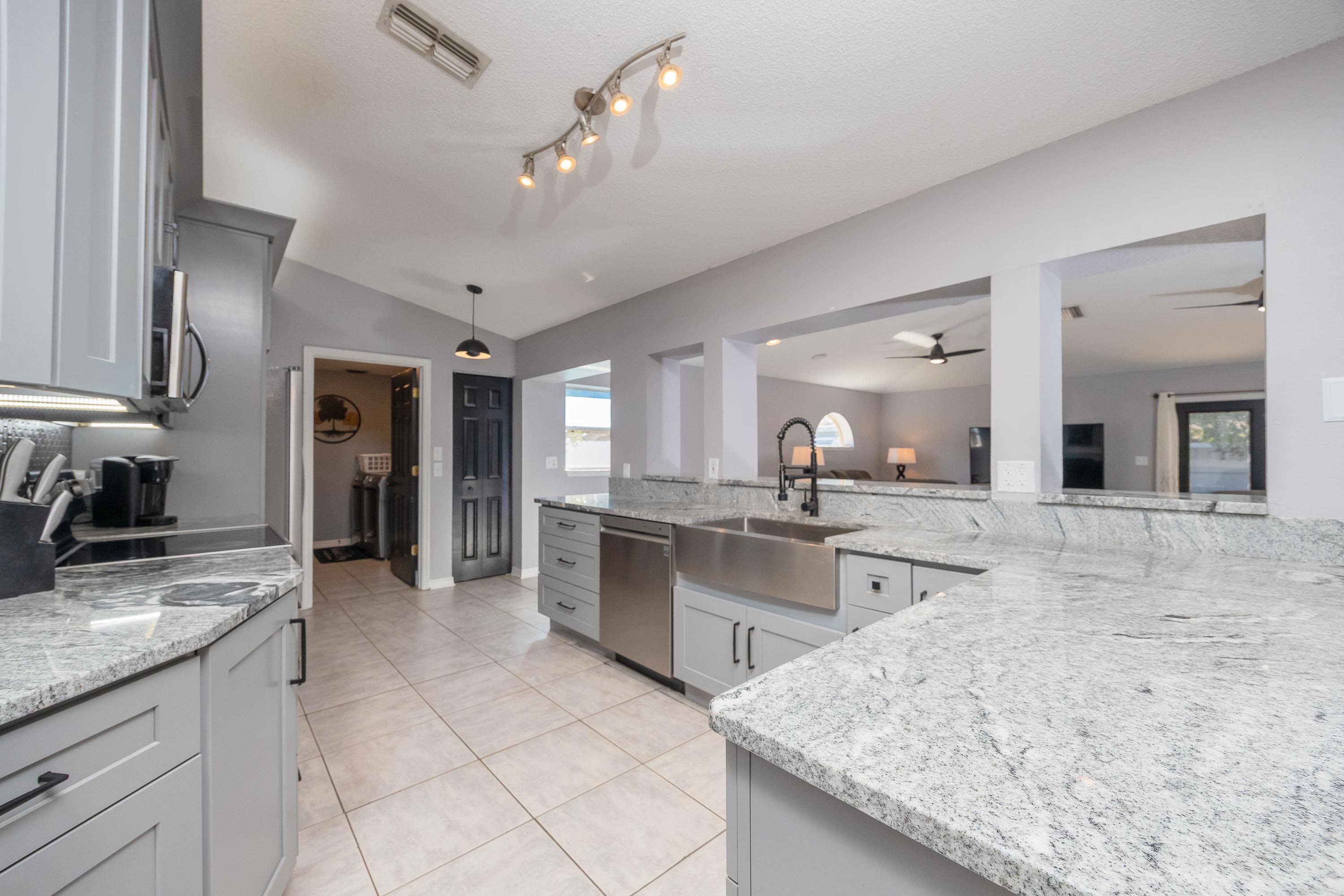 5 Rippling Place Palm Coast, FL 32164 - Photo 3 of 50 Kitchen with vaulted ceiling, light stone countertops, decorative light fixtures, appliances with stainless steel finishes, and light tile patterned floors