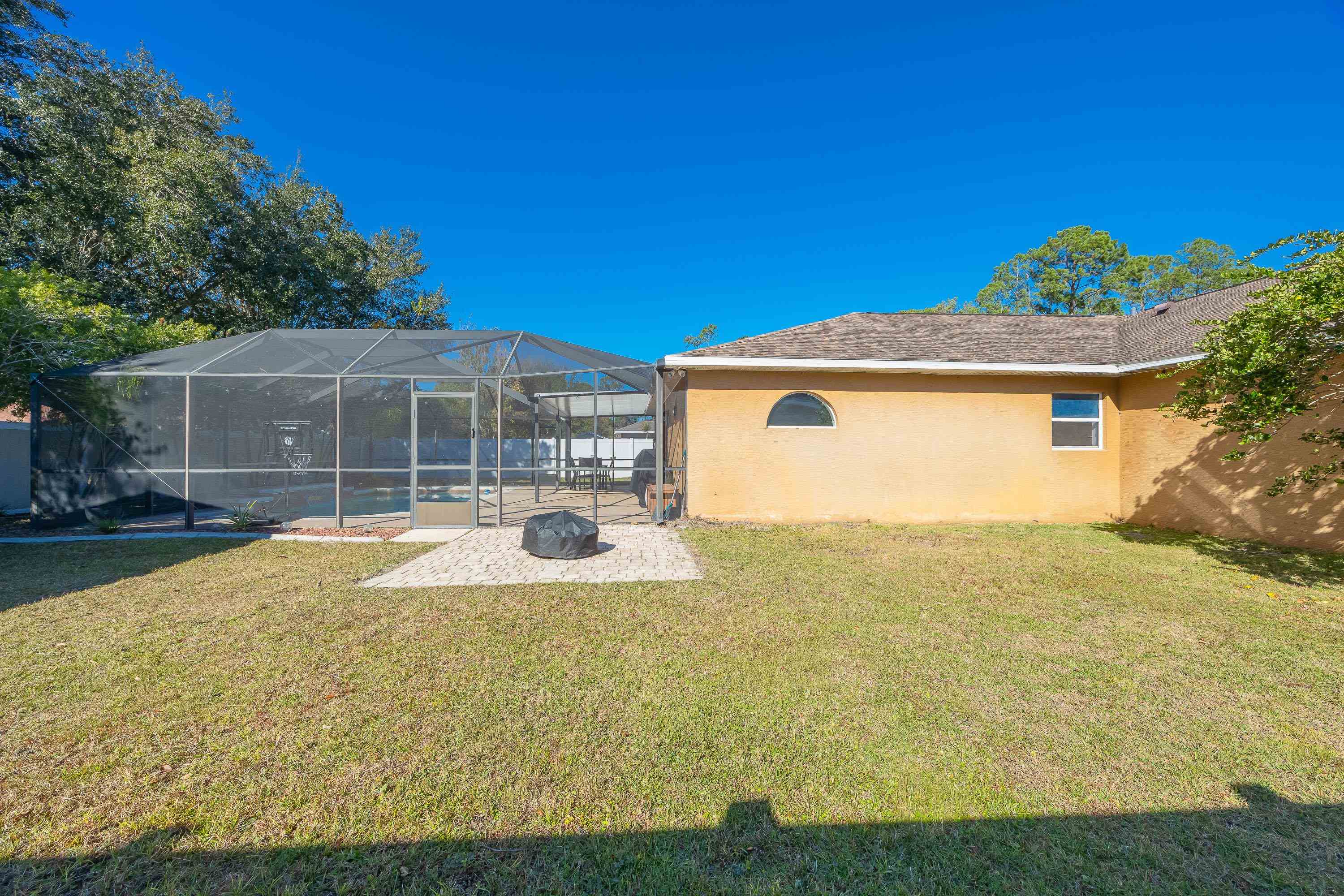 5 Rippling Place Palm Coast, FL 32164 - Photo 32 of 50 View of green lawn with a lanai, a pool, a sunroom, and a patio