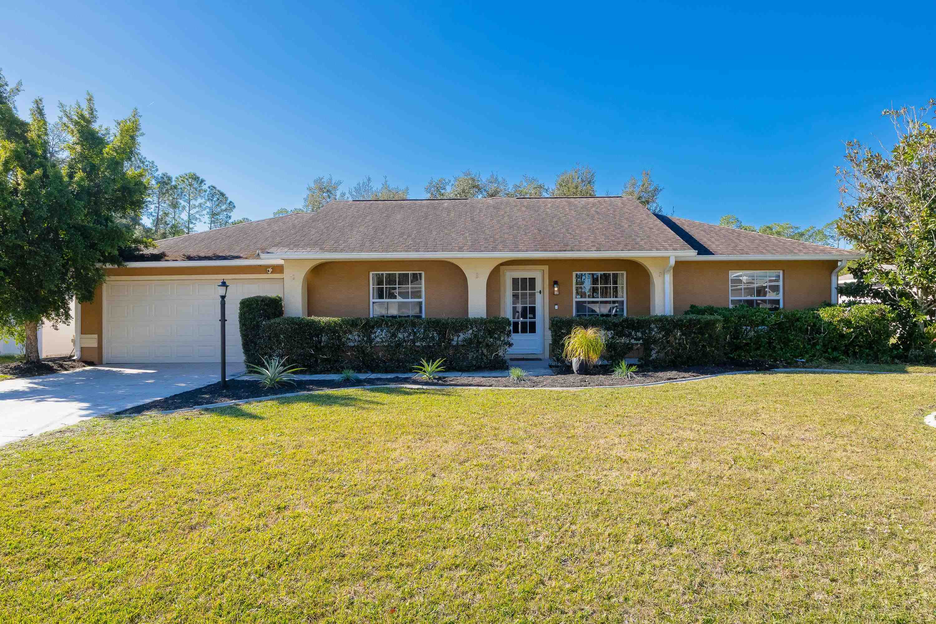 5 Rippling Place Palm Coast, FL 32164 - Photo 4 of 50 Ranch-style house featuring a front yard, stucco siding, concrete driveway, a garage, and covered porch