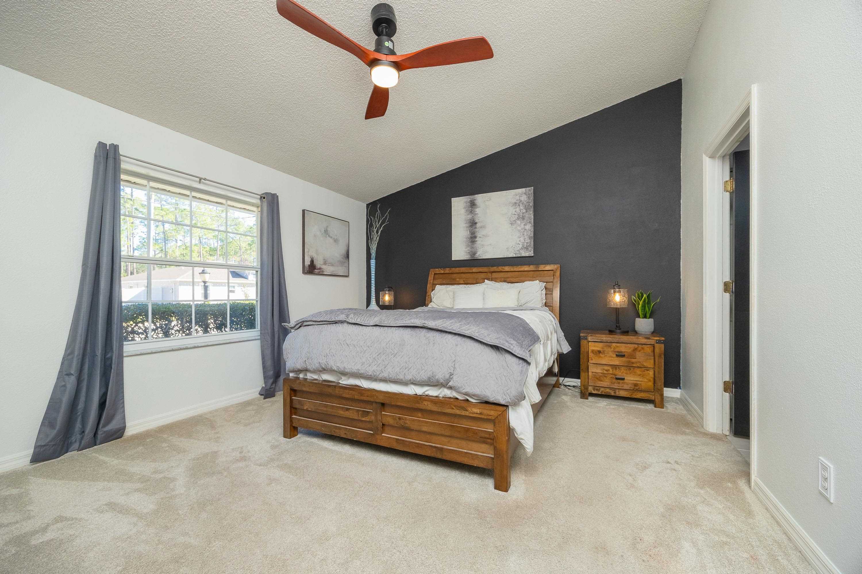 5 Rippling Place Palm Coast, FL 32164 - Photo 45 of 50 Carpeted bedroom with vaulted ceiling, a ceiling fan, a textured ceiling, and an accent wall