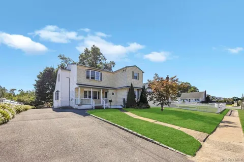 a view of a house with a big yard with plants and large trees