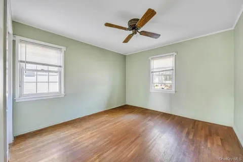 an empty room with wooden floor closet and windows