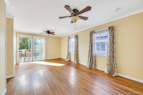 a view of an empty room with a window and wooden floor
