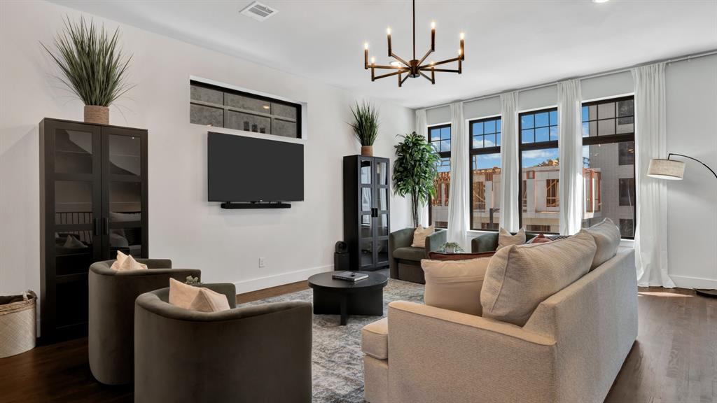 602 Winners Circle Rowlett, TX 75088 - Photo 8 of 35 Spacious living area featuring dark wood-finish flooring, a modern chandelier, and multiple tall windows with white drapes