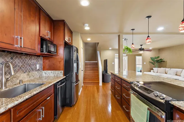 a kitchen with stainless steel appliances granite countertop a sink a stove and a wooden floors