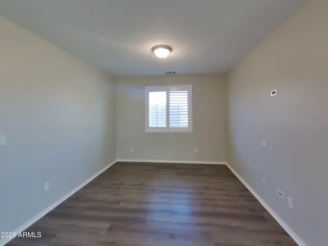 an empty room with wooden floor chandelier and windows