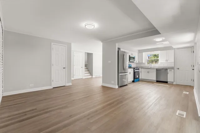 an empty room with wooden floor and entrance and windows