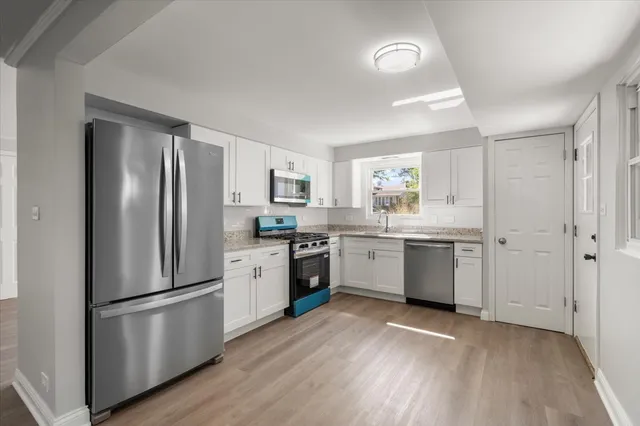 a kitchen with a refrigerator a sink dishwasher a stove and white cabinets with wooden floor