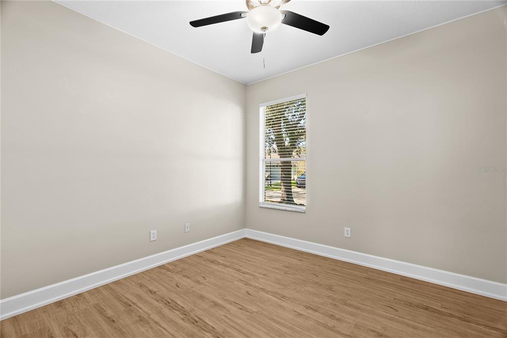 5012 Mirror Ridge Court Lutz, FL 33558 - Photo 28 of 44 an empty room with wooden floor chandelier fan and windows