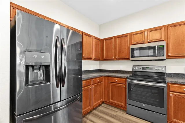 a kitchen with granite countertop a refrigerator stove and microwave