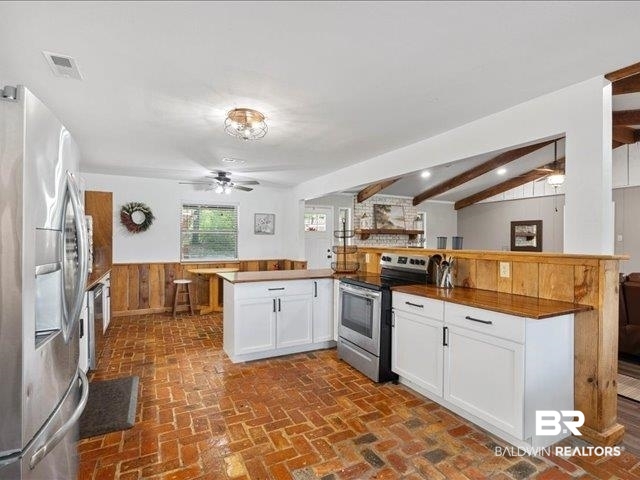 4650 Wiggins Lane Wilmer, AL 36587 - Photo 10 of 66 Kitchen with white cabinets, stainless steel appliances, brick floors, wooden walls, and ceiling fan