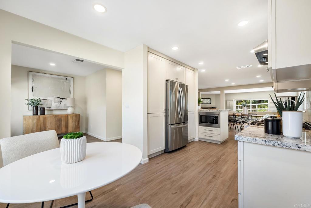 3163 Via De Caballo Encinitas, CA 92024 - Photo 5 of 23 a kitchen with stainless steel appliances a refrigerator a stove a sink a dining table and chairs with wooden floor