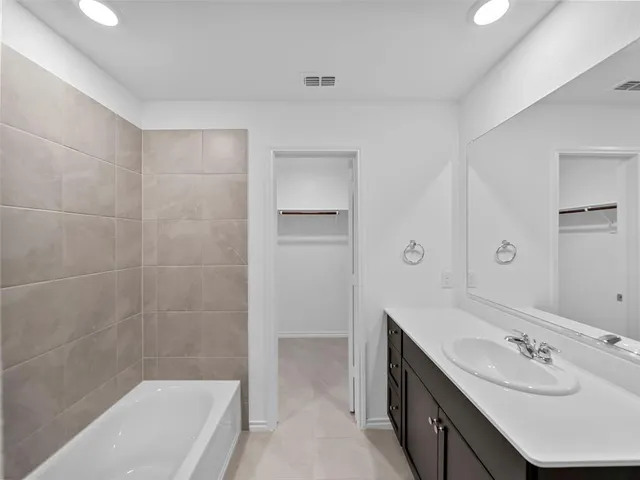 a bathroom with a tub sink shower and mirror