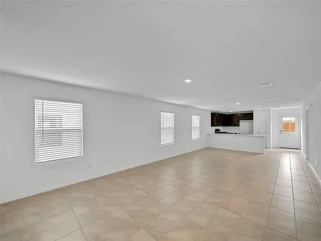 a view of an empty room with a window and a kitchen