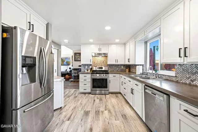 a kitchen with stainless steel appliances granite countertop a refrigerator a stove top oven and sink