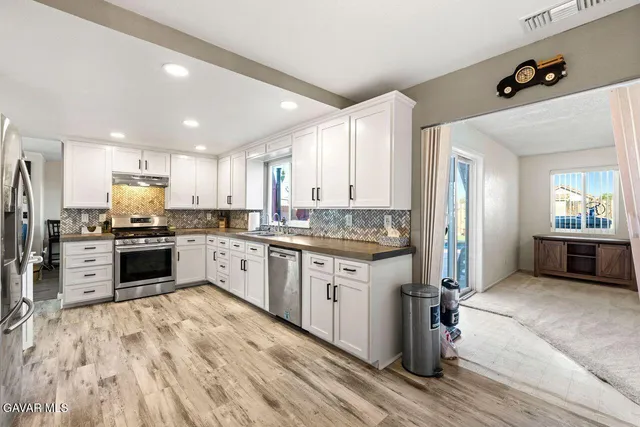 a kitchen with granite countertop white cabinets and stainless steel appliances