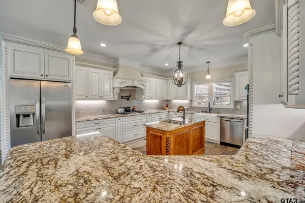 a kitchen with stainless steel appliances kitchen island granite countertop a sink a stove and a refrigerator