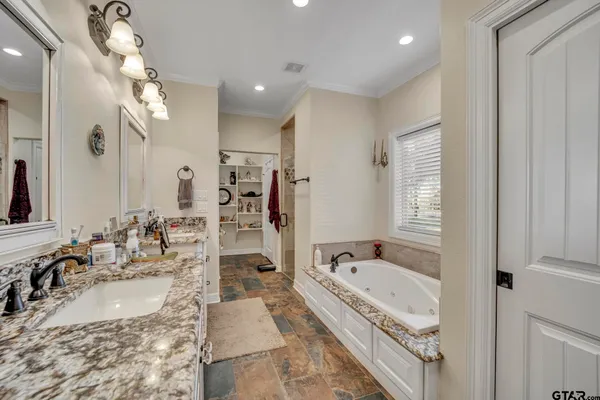 a bathroom with a granite countertop tub sink and mirror