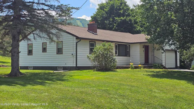 a view of a house with backyard and a tree