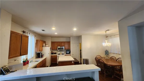 a large kitchen with sink a refrigerator and chairs