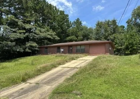 a front view of house with yard and trees all around