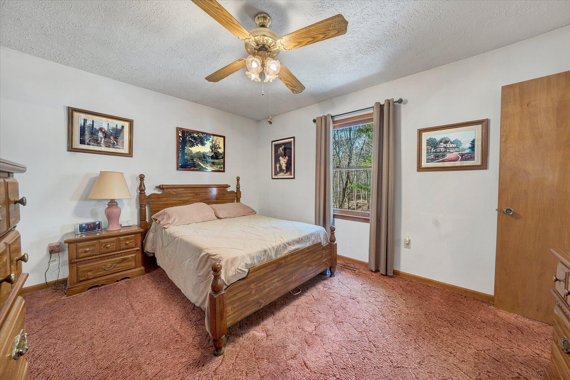 98 Sunset Ridge Road Callaway, VA 24067 - Photo 14 of 32 a bedroom with a large bed and a chandelier