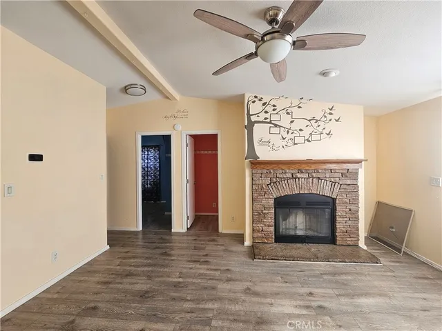 a view of an empty room with chandelier fan and fire place