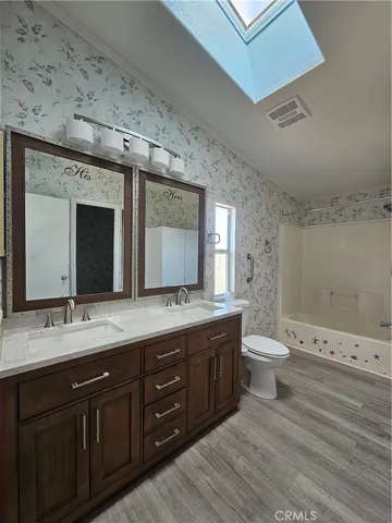 a spacious bathroom with a granite countertop toilet sink and mirror