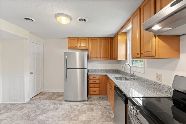 a kitchen with stainless steel appliances granite countertop a refrigerator a sink and a stove