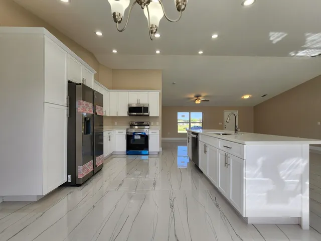 a large kitchen with stainless steel appliances kitchen island a large counter top and a refrigerator