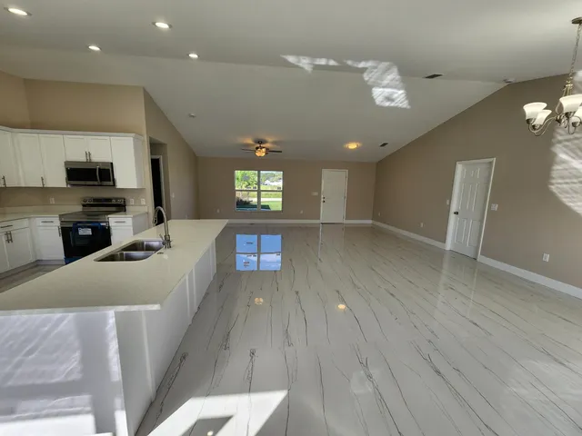 a large kitchen with cabinets a sink dishwasher a dining table and chairs with wooden floor