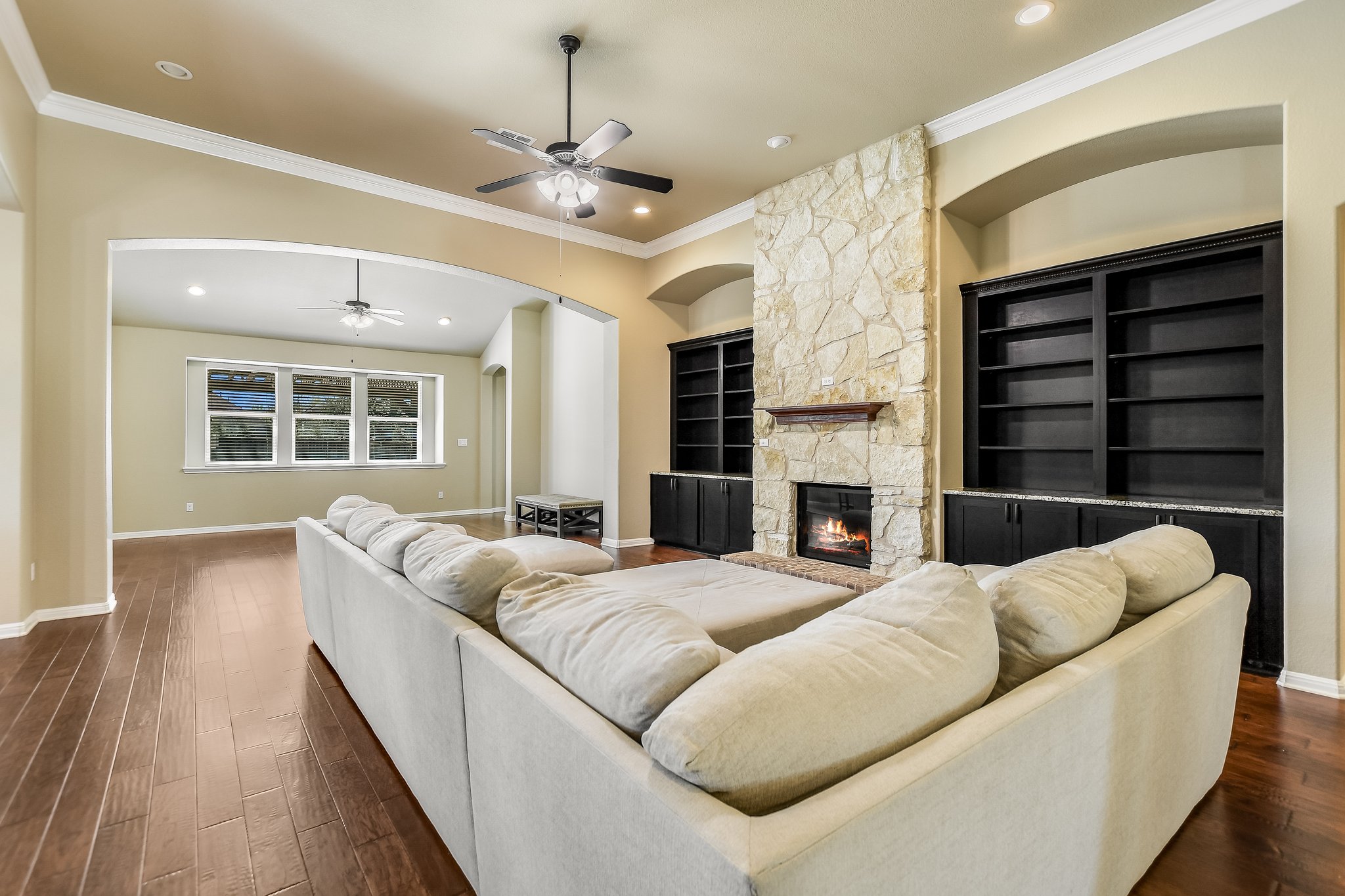 2037 Tribal Way Leander, TX 78641 - Photo 8 of 14 This family room has hardwood floors, a stone fireplace, and built-in cabinets with bookshelves, and crown moulding