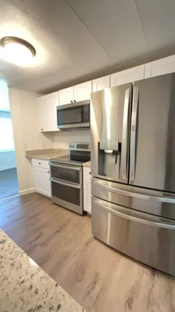 a kitchen with granite countertop a refrigerator and a stove top oven