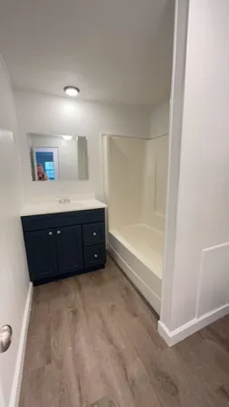 a spacious bathroom with a tub sink and mirror