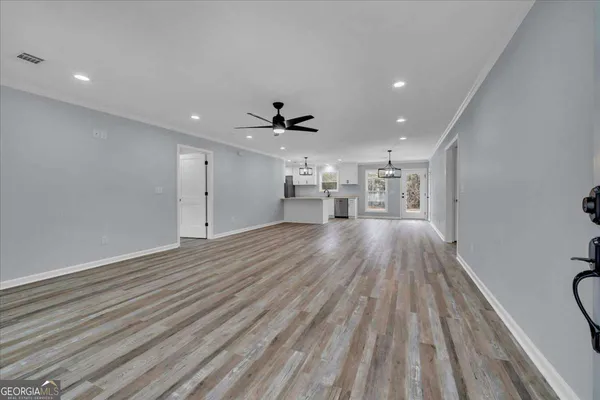 a view of an empty room with wooden floor and windows