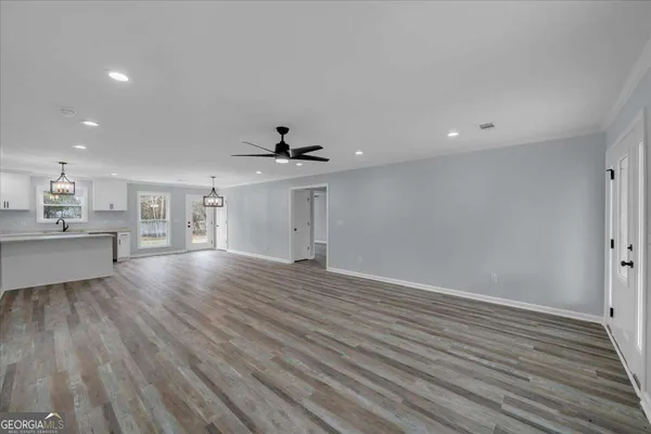 a kitchen with stainless steel appliances granite countertop a refrigerator a stove oven a sink dishwasher and white cabinets with wooden floor