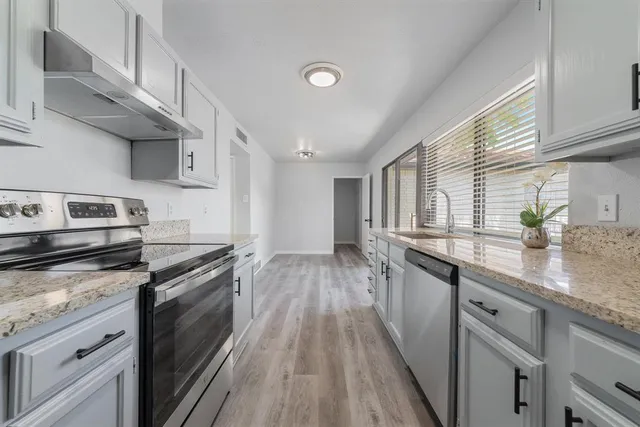 a kitchen with granite countertop wooden floors and stainless steel appliances