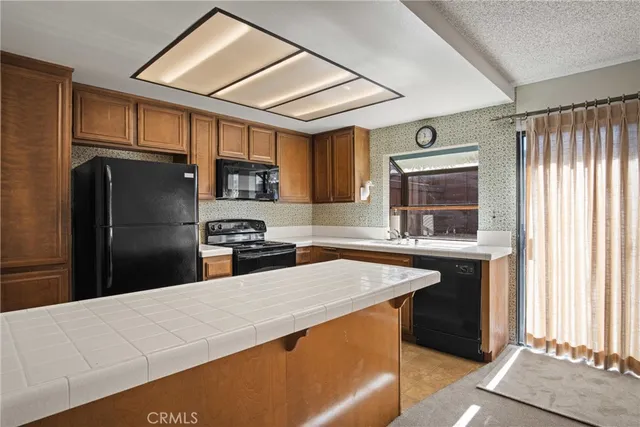 a kitchen with stainless steel appliances granite countertop a refrigerator a sink dishwasher a stove and white cabinets with wooden floor