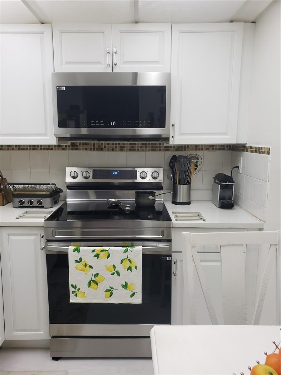 11800 Southwest 18th Street, Unit 3274 Miami, FL 33175 - Photo 8 of 23 a kitchen with stainless steel appliances a stove a microwave and cabinets