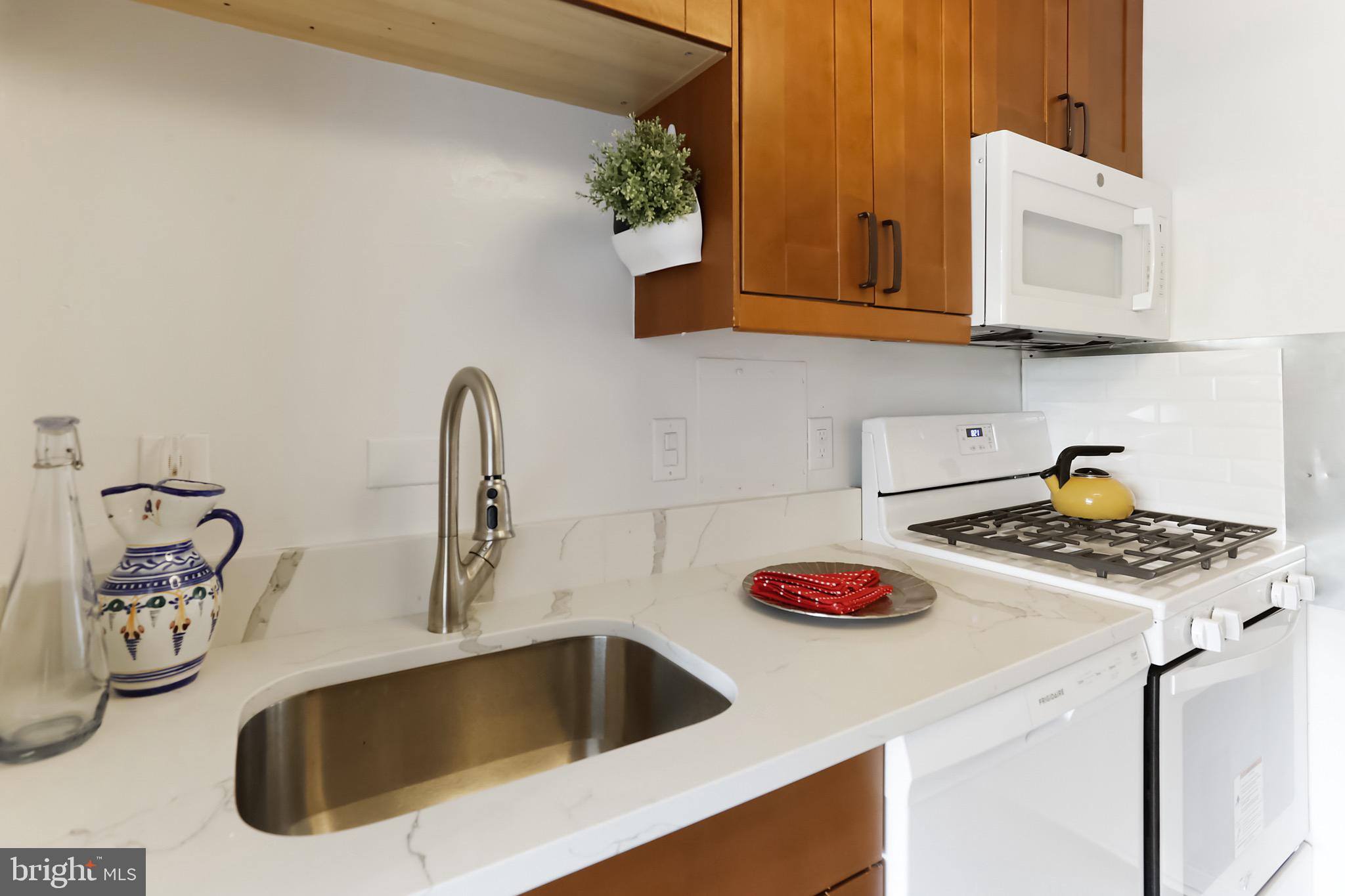 1900 Lyttonsville Road, Unit 802 Silver Spring, MD 20910 - Photo 30 of 38 a kitchen with white cabinets a sink and a stove with wooden floor