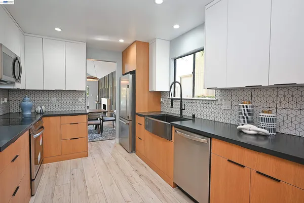 a kitchen with stainless steel appliances granite countertop a sink stove refrigerator and cabinets