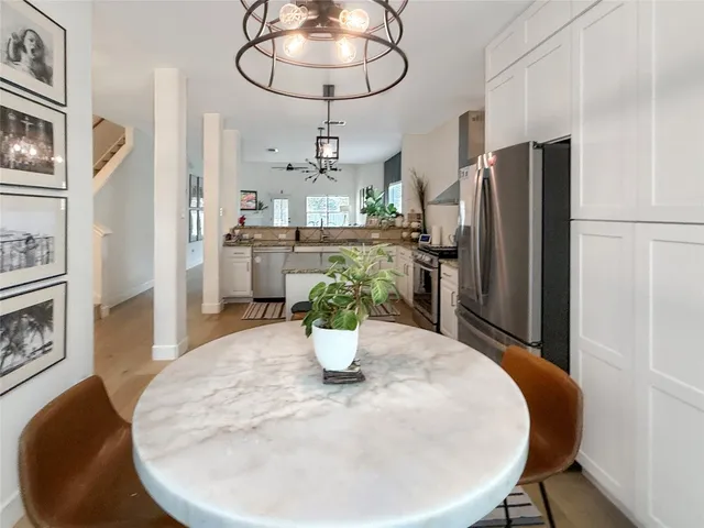 a kitchen with stainless steel appliances a dining table chairs and refrigerator